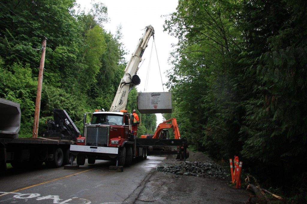 Using the crane truck to move culvert sections into place.