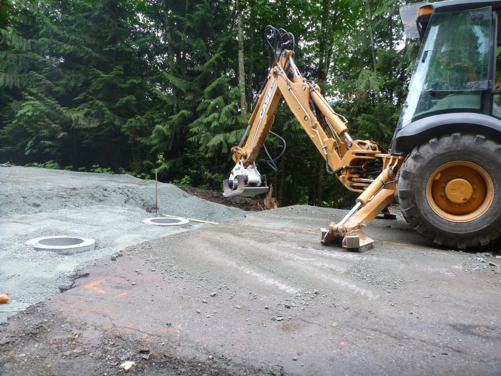 Compacting road base over culvert to create solid foundation for paving.