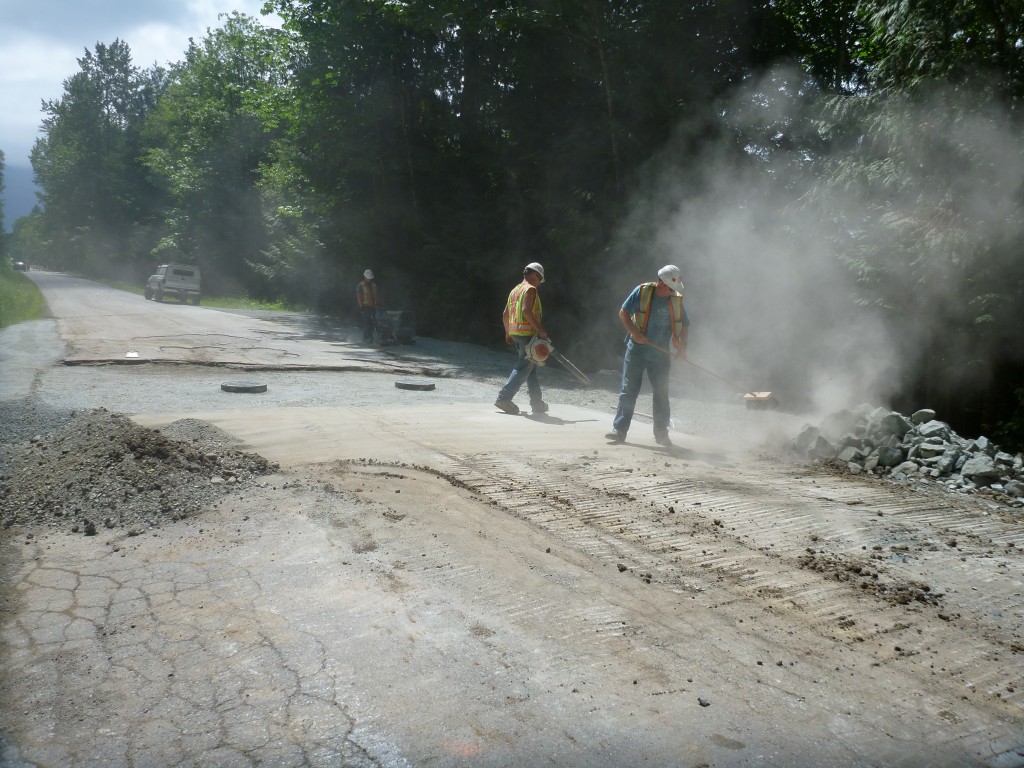 Cleaning up the road and compacting the road base.